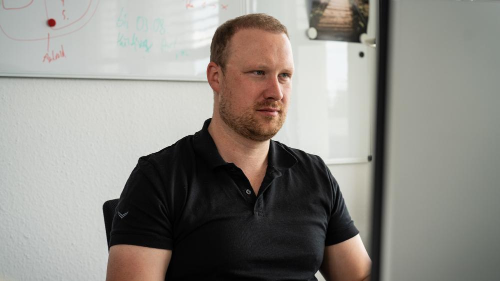 Ein Mann sitzt konzentriert vor einem Laptop und steht für die menschliche Firewall im Unternehmen.