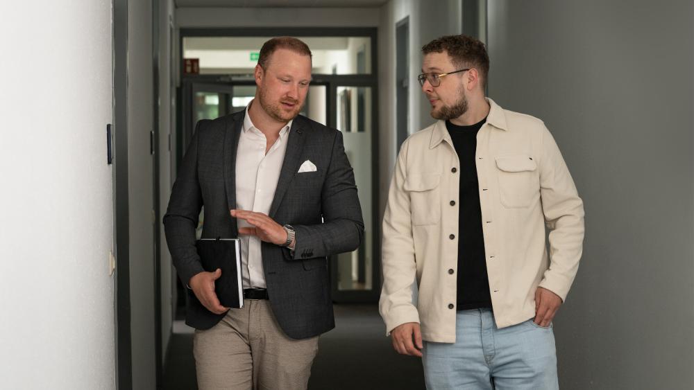 Zwei Männer im Flur diskutieren über Krisenübungen testen.