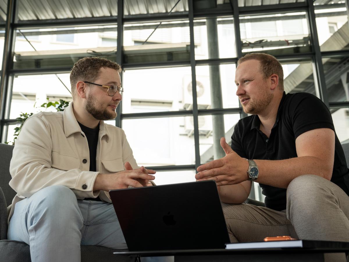 Zwei Männer diskutieren über Cybersicherheit in modernen Büroräumen.