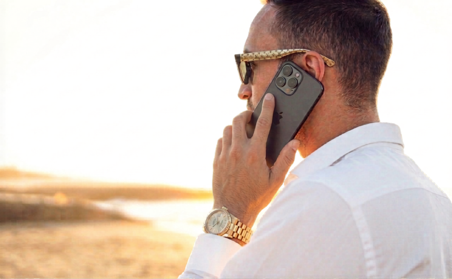 Mann in weißem Hemd telefoniert am Strand und plant Amazon-Händler-Strategie.