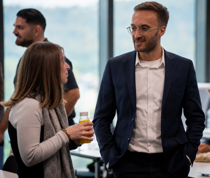 Zwei Personen im Gespräch während einer Networking-Veranstaltung, mit Fokus auf der Amazon FBA Produktsuche.