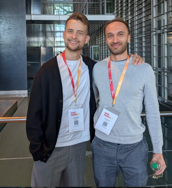 Zwei Männer mit Lanyards stehen lächelnd bei einem Event zur Themen Amazon-Team aufbauen.