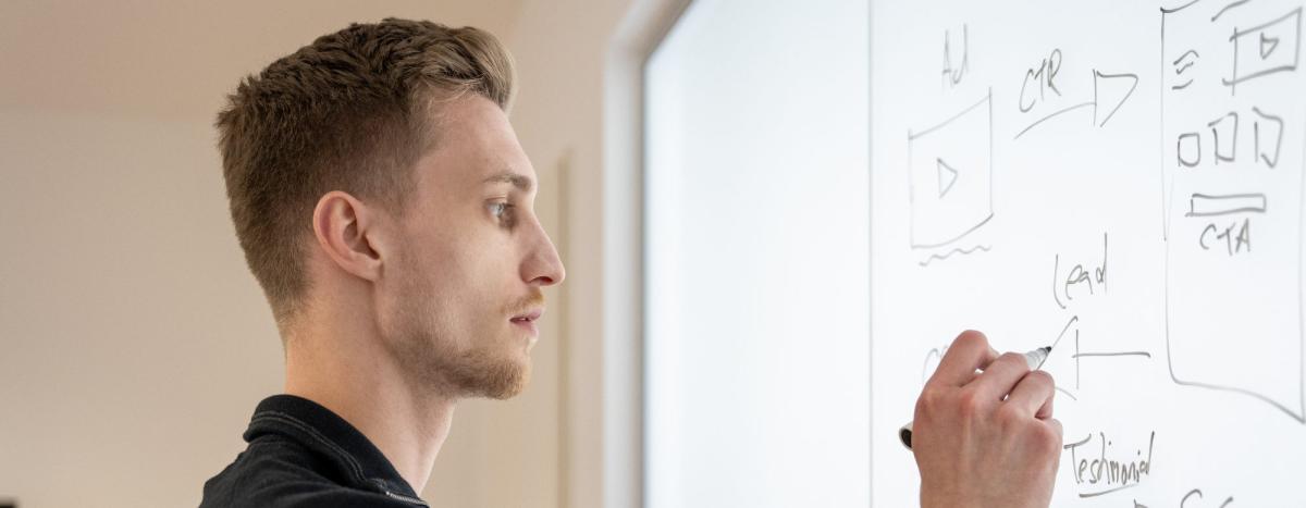 Junger Mann analysiert Video-Testimonials Marketing auf einem Whiteboard.
