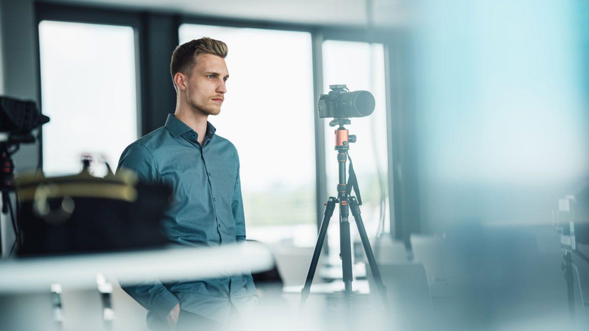 Ein Mann steht vor einer Kamera, die für Video-Testimonials vorbereitet ist.