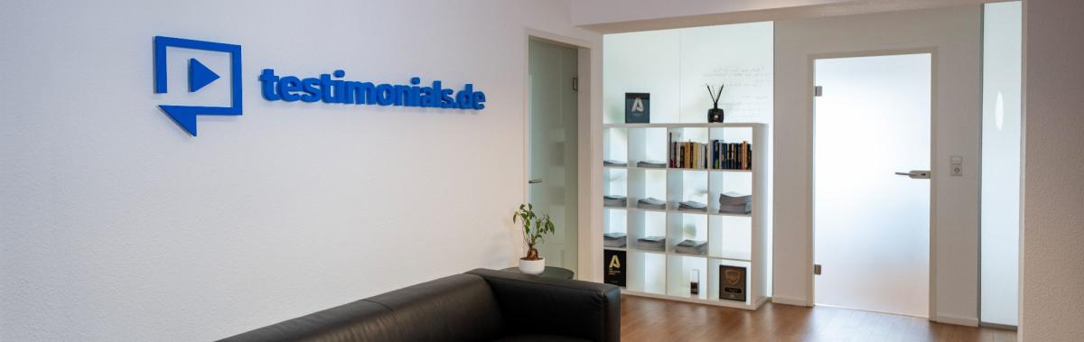 Büro von testimonials.de mit Logo und modernen Möbeln.