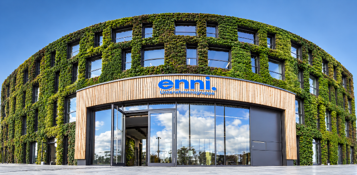 Das moderne Firmengebäude von enfi, einem Energieanbieter, mit grüner Pflanzenfassade.