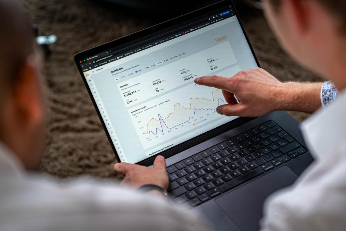 Zwei Personen analysieren auf einem Laptop die Performance von Werbeanzeigen.