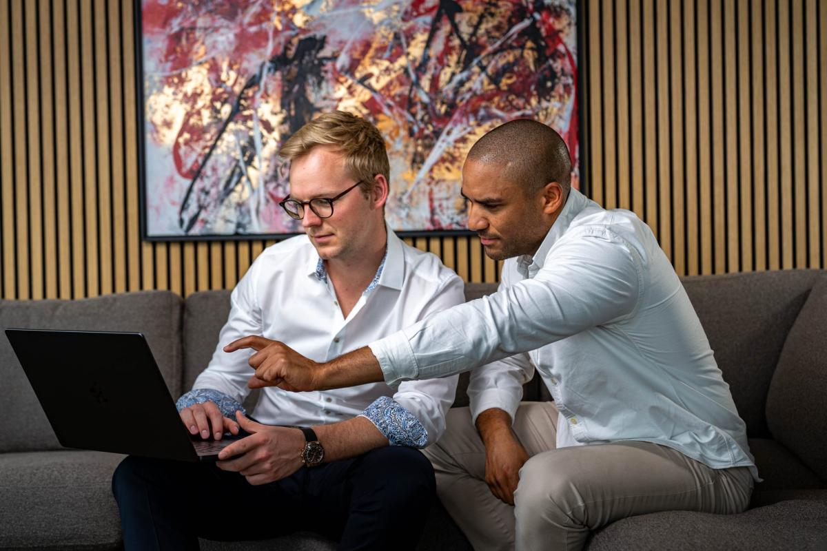 Zwei Personen besprechen die Zusammenarbeit mit einer Marketing-Agentur am Laptop.