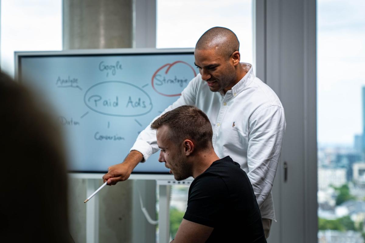 Ein Mitarbeiter erklärt eine Strategie zu Paid Ads während einer Besprechung.
