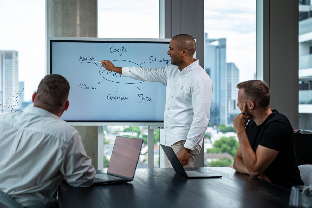 Ein Mann erklärt in einer Präsentation die Vorteile bezahlter Werbung während eines Meetings.