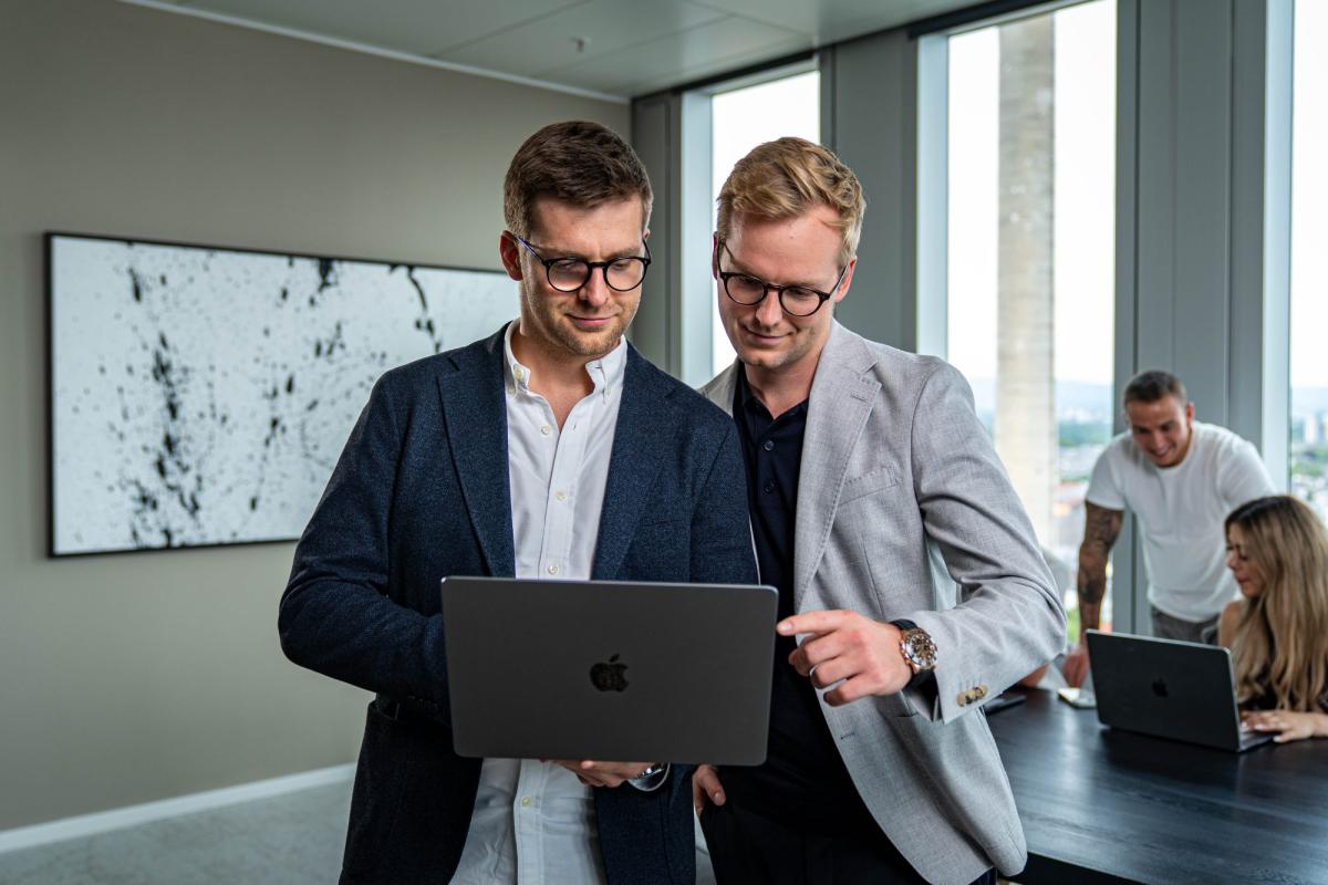 Zwei Berater analysieren gemeinsam am Laptop die Ergebnisse von Kaltakquise.