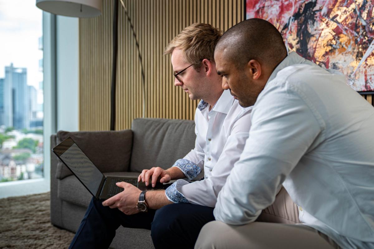 Zwei Männer analysieren datengetriebene Werbung an einem Laptop.