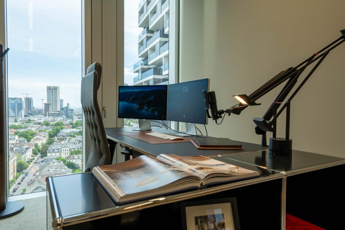 Ein modernes Büro mit einem Schreibtisch, Monitor und Stadtblick zur Analyse des Werbebudgets.