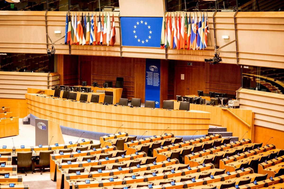 Innenansicht des europäischen Parlaments mit Flaggen und Sitzen.