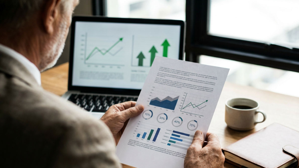 Ein Investor analysiert Marktdaten mit Charts zur INVESTICOM 2026.