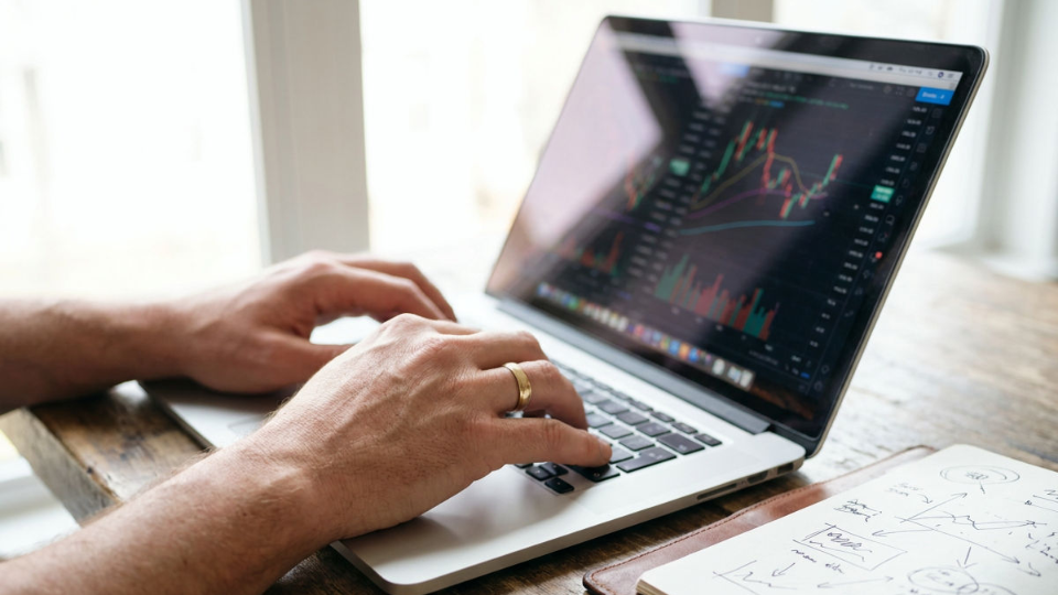 Ein Trader analysiert Charts und Daten auf seinem Laptop, um Geld zum Traden zu investieren.