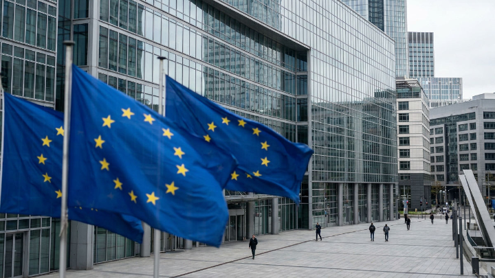 CRD VI betrifft grenzüberschreitende Bankgeschäfte; EU-Flaggen wehen vor einem modernen Glasgebäude.