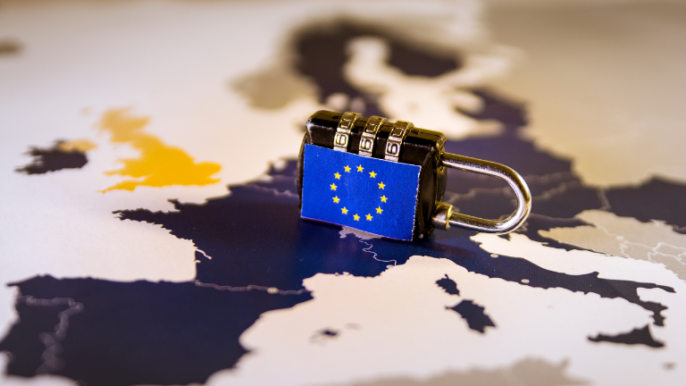 Ein Vorhängeschloss mit EU-Flagge liegt auf einer Europakarte – Symbol für Vermögen internationalisieren.