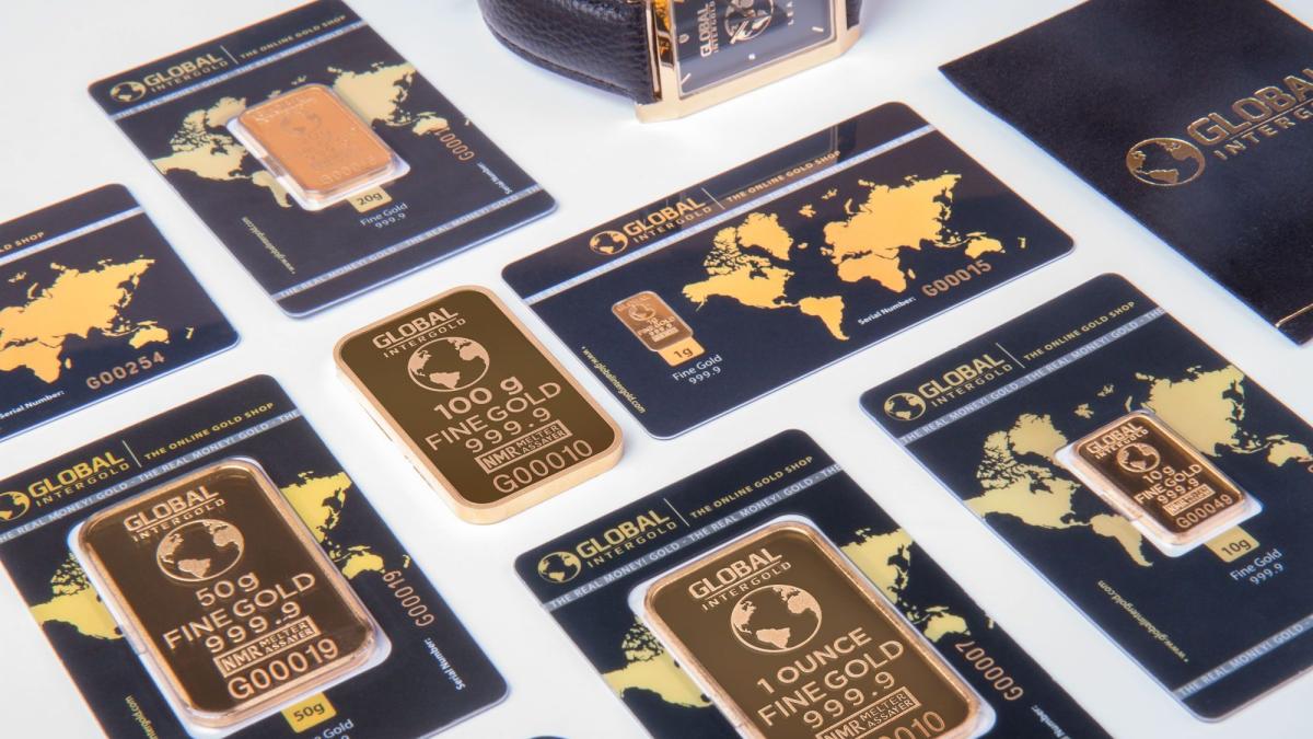 Sammlung physischer Sachwerte mit Goldbarren und Karten.