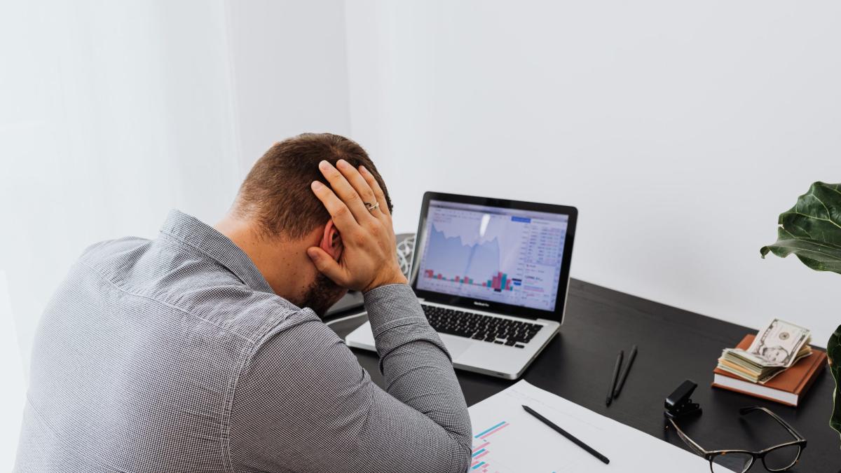 Mann in Stress am Schreibtisch mit Laptop, zeigt Herausforderungen beim Vermögen über Generationen.