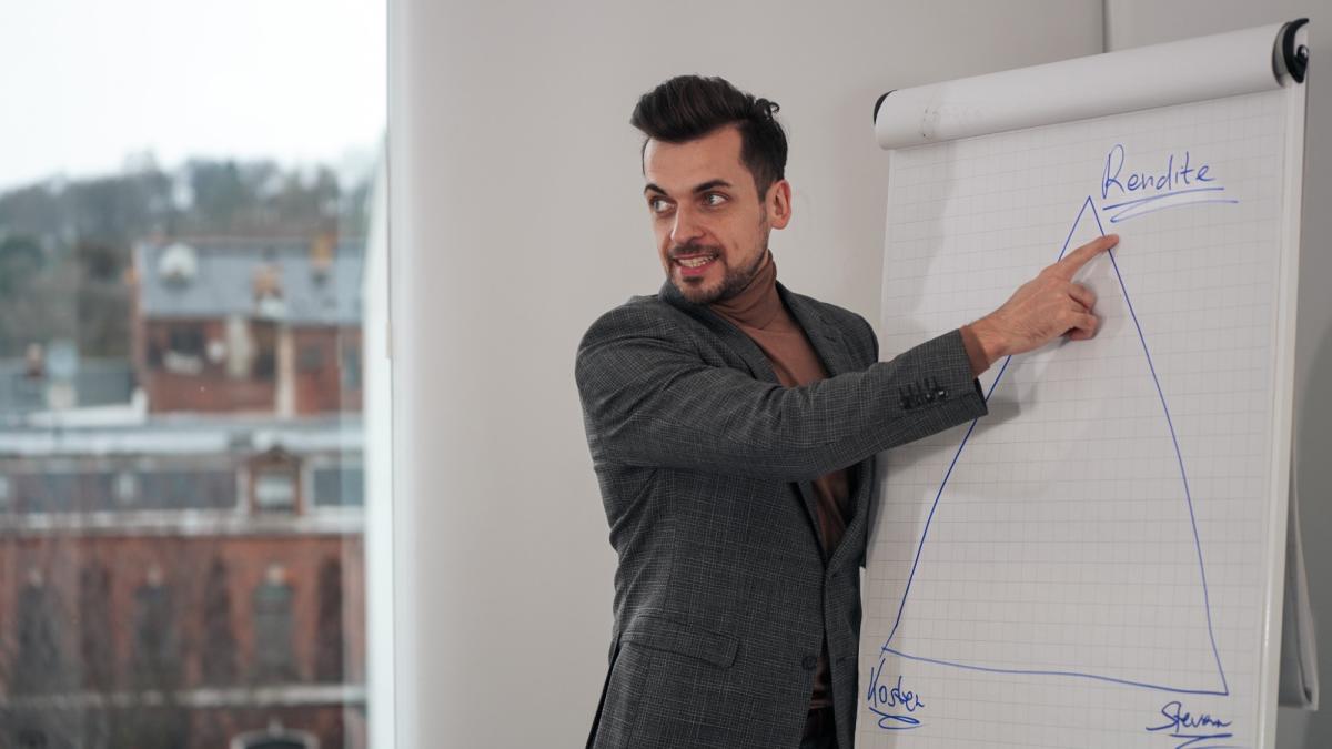 Ein Handwerksmeister zeigt auf ein Diagramm während einer Präsentation zum Thema investieren.
