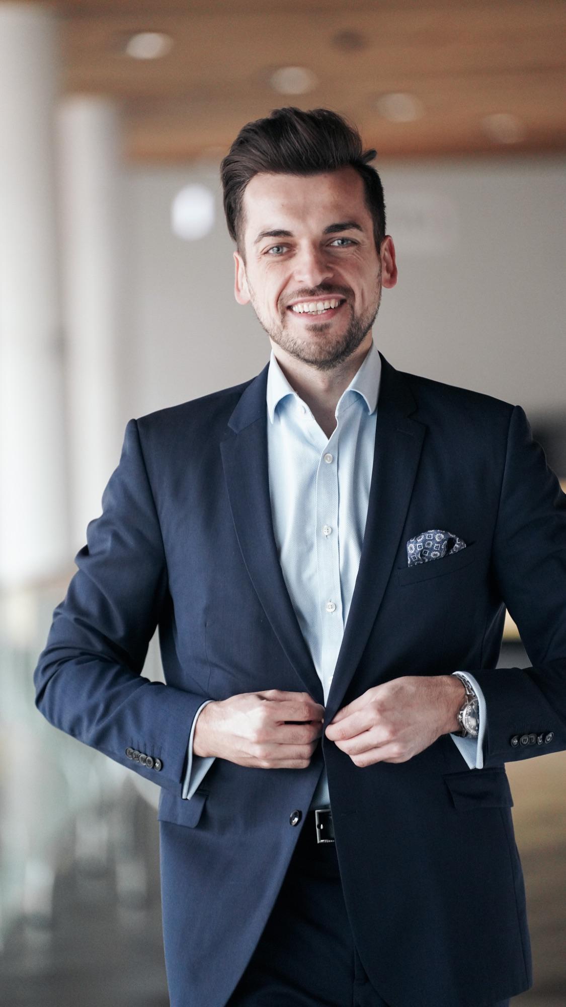 Ein professioneller Anleger im Anzug steht lächelnd und vertrauenerweckend da, ideal für den DekaFonds Global Champions.