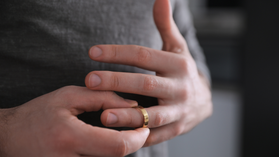 Mann nimmt seinen Hochzeit-Ring ab, symbolisch für Unterhalt legal reduzieren.