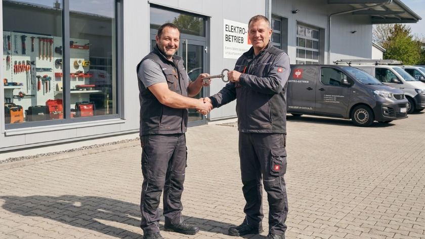 Zwei Handwerksmitarbeiter beim Unternehmensverkauf im Handwerk, die Hände schütteln.
