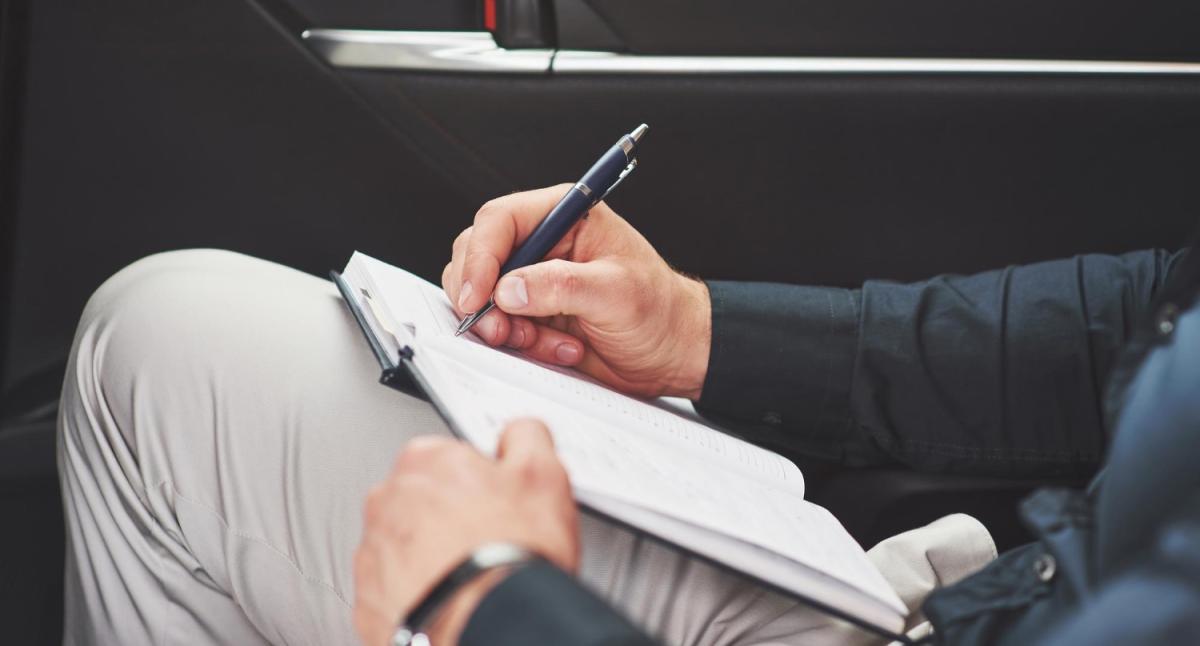 Eine Person notiert wichtige Informationen bezüglich Firmenwagen in der GmbH.