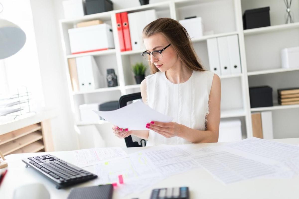 Eine Frau prüft Unterlagen am Arbeitsplatz, während sie Gutscheine als Sachbezug betrachtet.