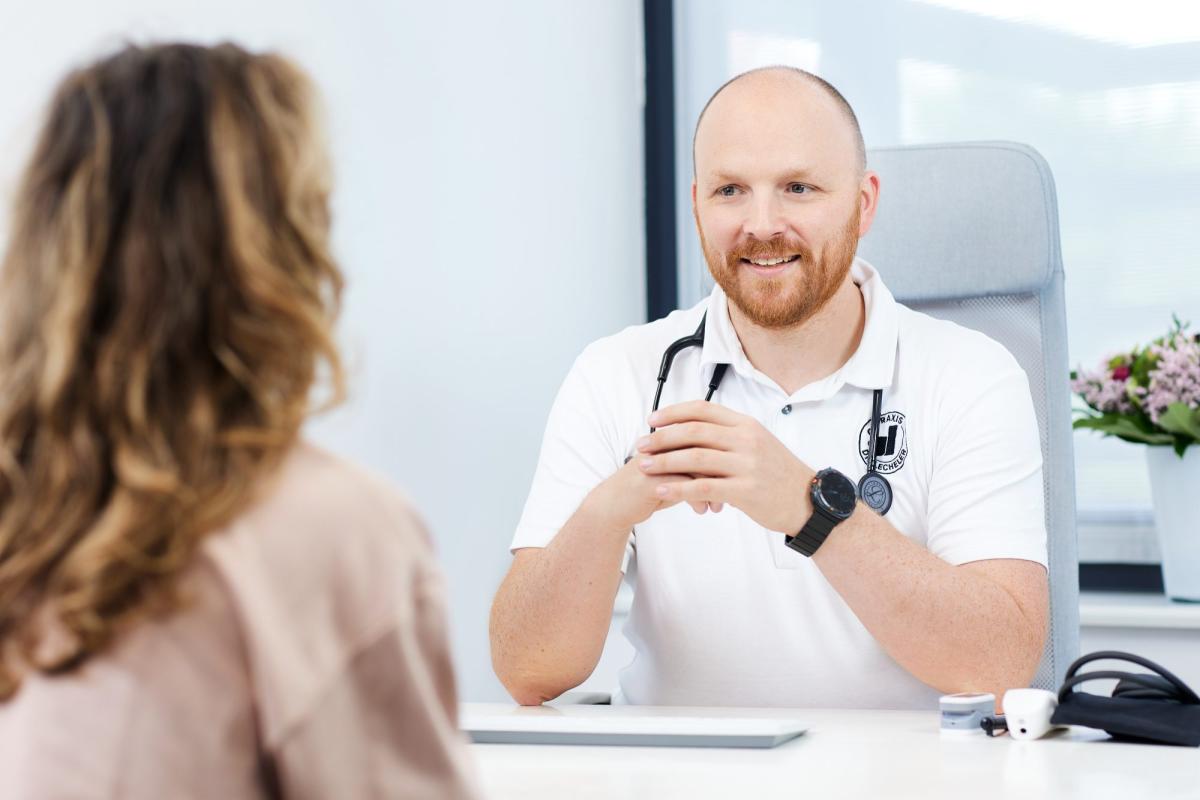 Arzt spricht über KI Erschöpfung mit Patientin im Sprechzimmer.