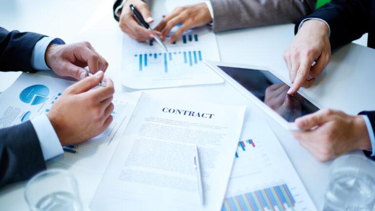 Vier Hände analysieren einen Vertrag zur Prisma FlexInvest Altersvorsorge.