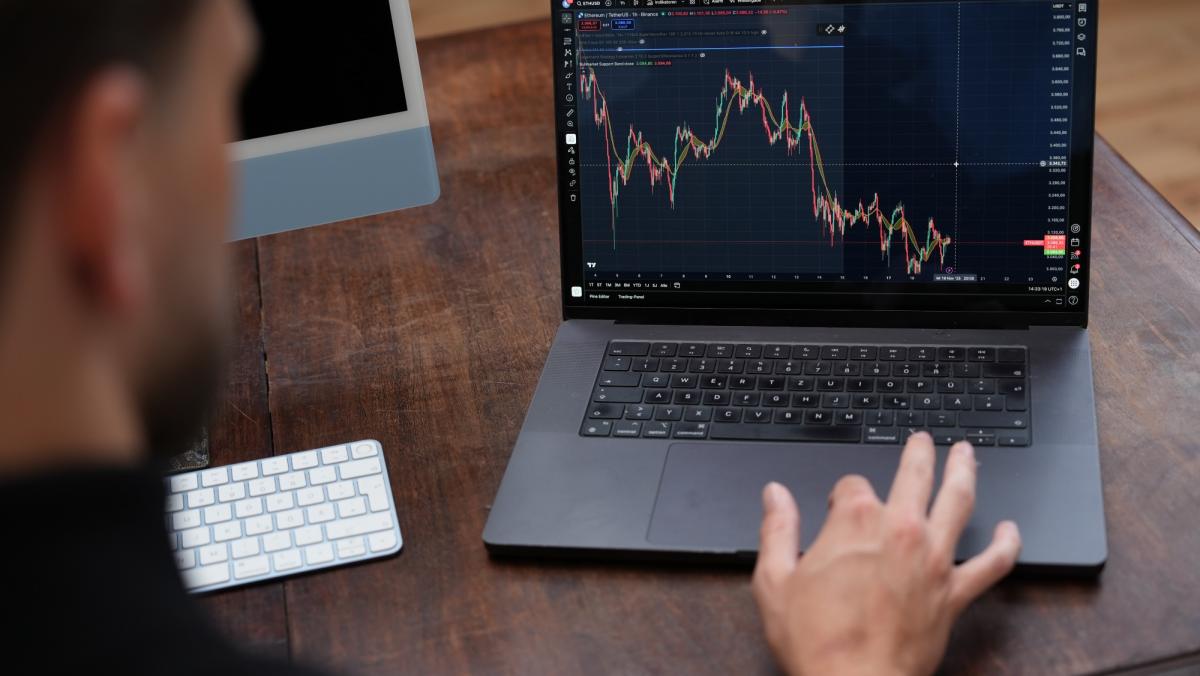Junger Mann analysiert Börsendaten auf Laptop im Trading.