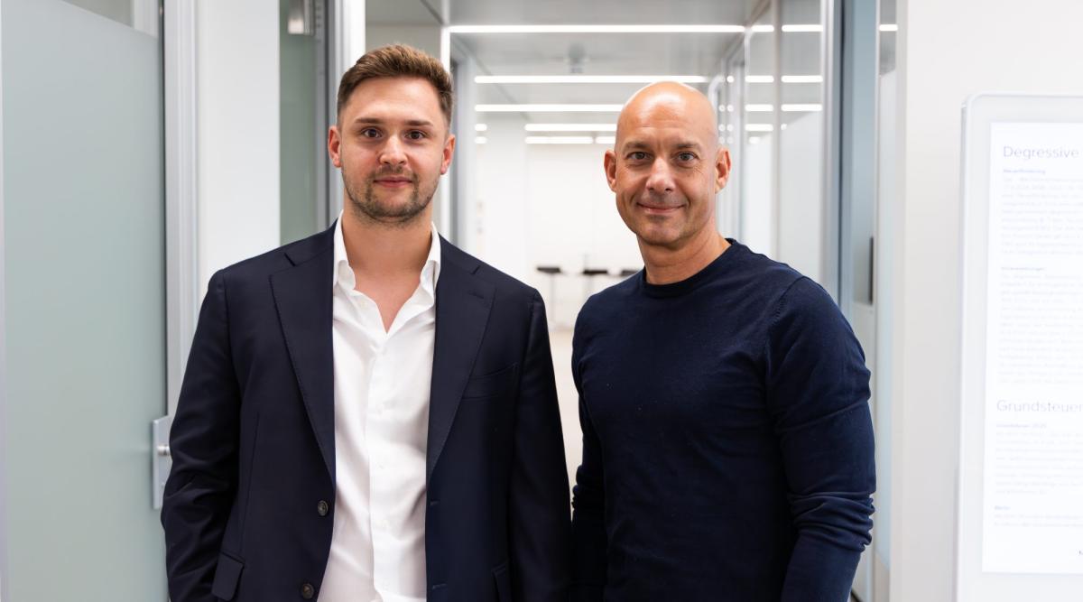 Zwei Männer stehen in einem modernen Büro und sprechen über Mandantengewinnung für Steuerkanzleien.