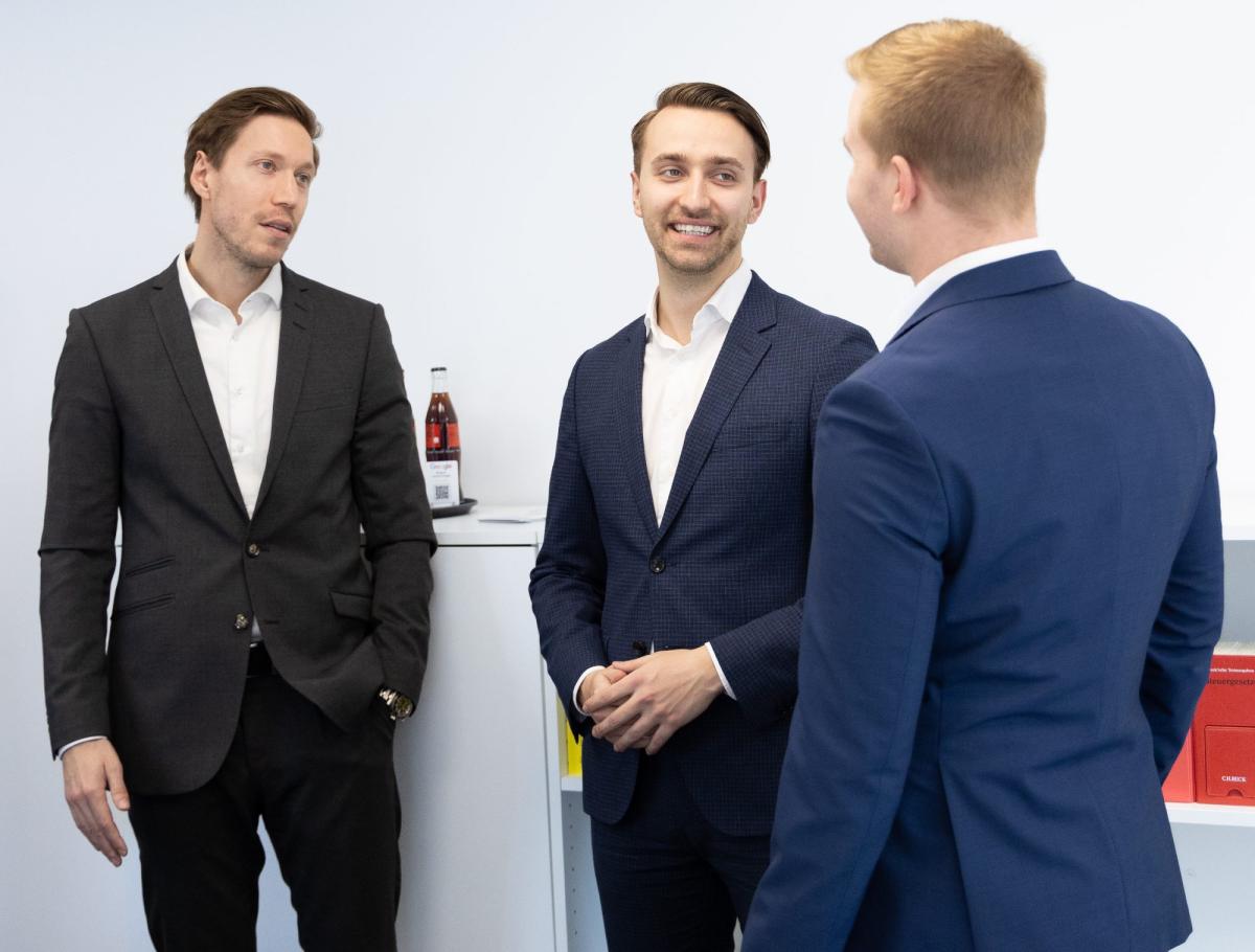 Drei männliche Berater im Gespräch über Mandanten-Onboarding.