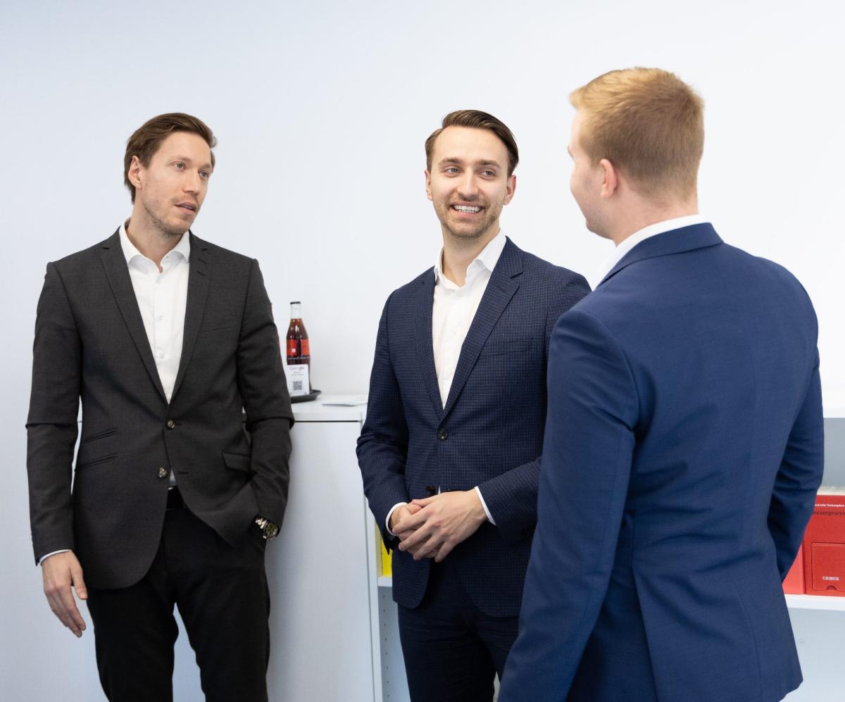 Drei Männer in Anzügen besprechen Strategien zur Mandantengewinnung für die Steuerkanzlei.