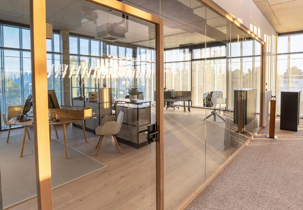 Moderner Büroraum mit Bürotrennwänden aus Glas und viel Tageslicht.