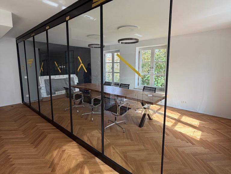 Moderne Bürotrennwand aus Glas in Augsburg mit Holzfußboden und Besprechungsraum.