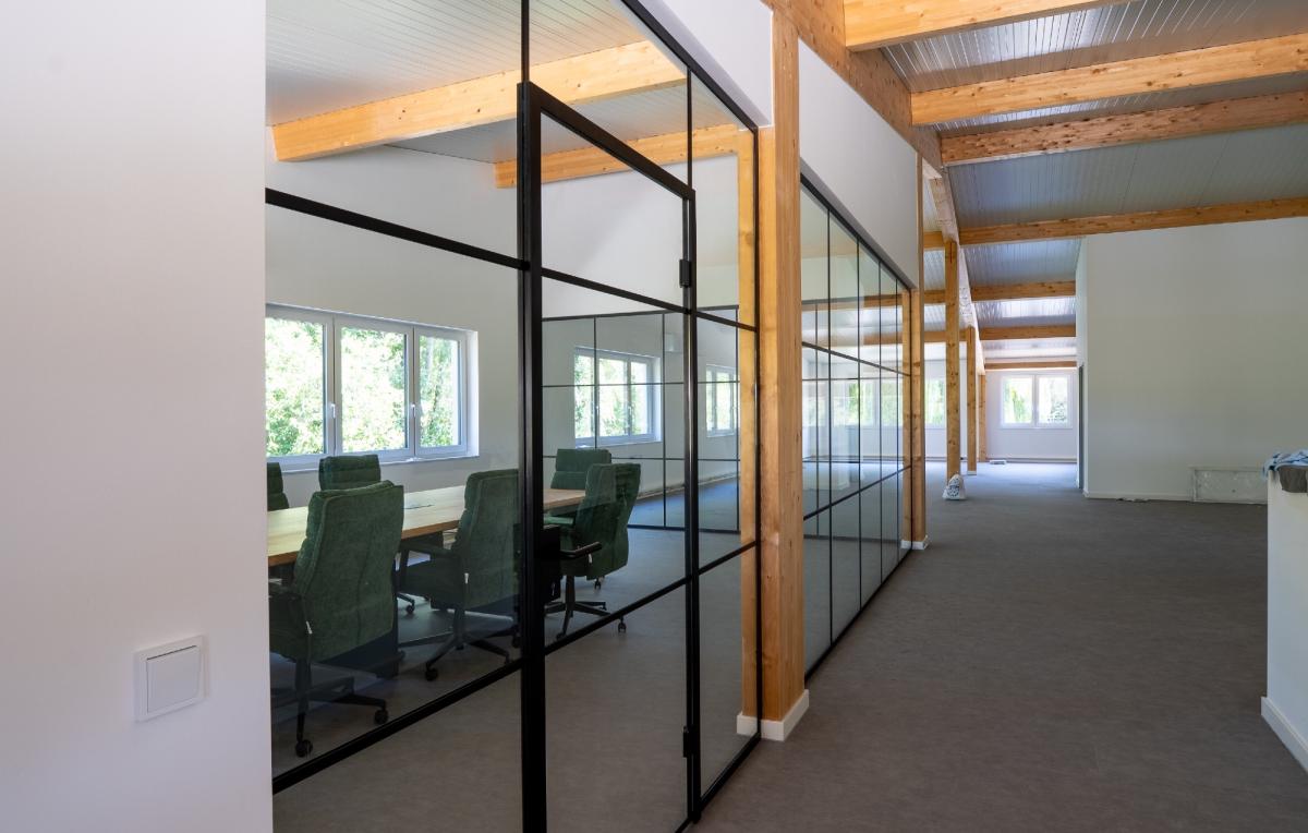 Moderne Bürotrennwand aus Glas in einem Raum mit Holzdecken.