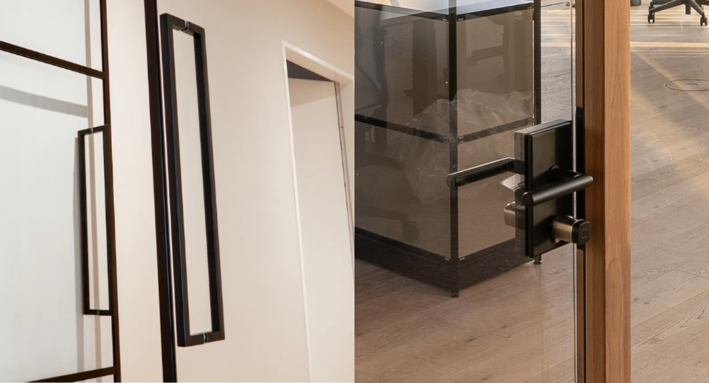 Glastrennwand mit Tür, links mit schwarzen Griffen und rechts mit dunklem Beschlag an einem Holzrahmen.