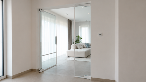 Glastrennwand mit geöffneter Pendeltür aus Klarglas zwischen Flur und Wohnzimmer.