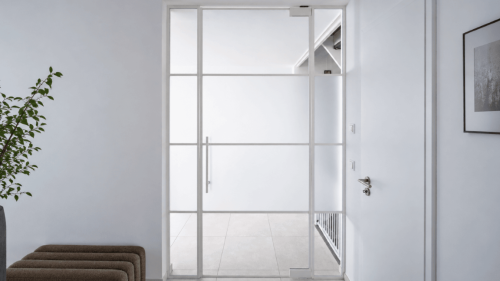 Loft-Trennwand mit weißen Profilen und feiner Sprossenteilung zwischen Wohnraum und Flur.