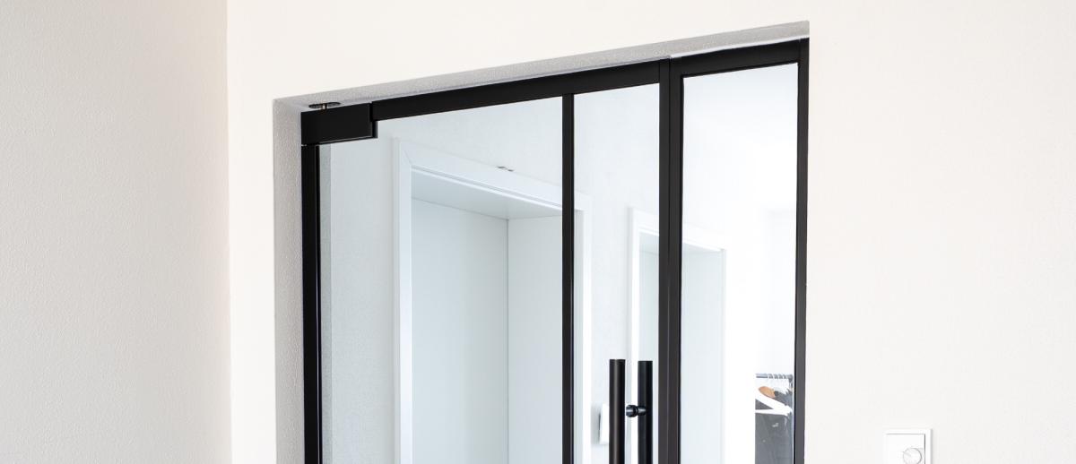 Glastrennwand Wohnzimmer mit schwarzem Rahmen und schmalen Sprossen in einem hellen Raum