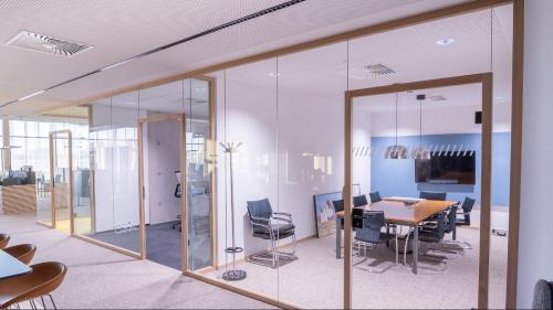 Helles Büroabteil, den schlanke schlanke Glastrennwände teilt, ohne Tageslicht zu nehmen.