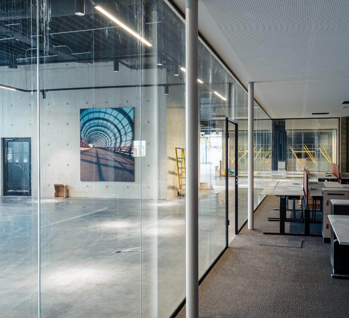 Akustik-Trennwand Büro aus Glas trennt offene Arbeitsplätze und Besprechungsbereiche.