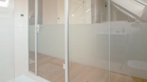 Dezenter Sichtschutz durch breiten Satinstreifen an der Glastrennwand fürs Badezimmer.