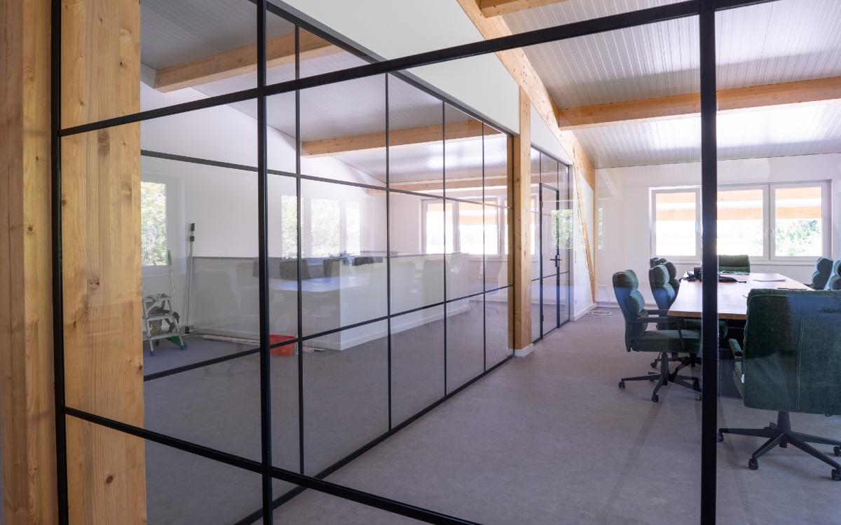 Moderne Loft-Trennwand aus Glas in einem Innenraum mit Besprechungstisch.