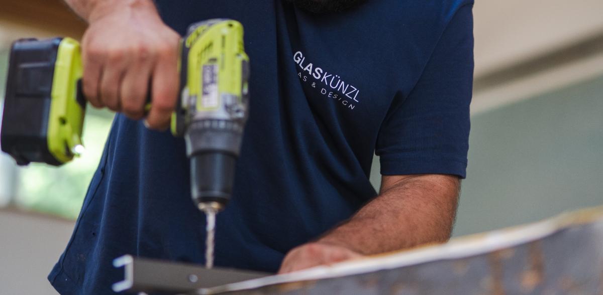 Handwerker bohrt mit einer Maschine bei der Montage einer Loft-Trennwand.