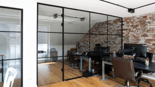 Raumhohe Loft-Trennwand mit schmalen dunklen Profilen und regelmäßiger Sprossenteilung.