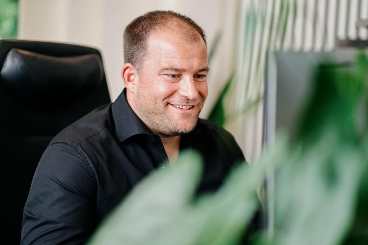 Ein Mitarbeiter lächelt im Büro und reflektiert über psychische Erkrankungen.